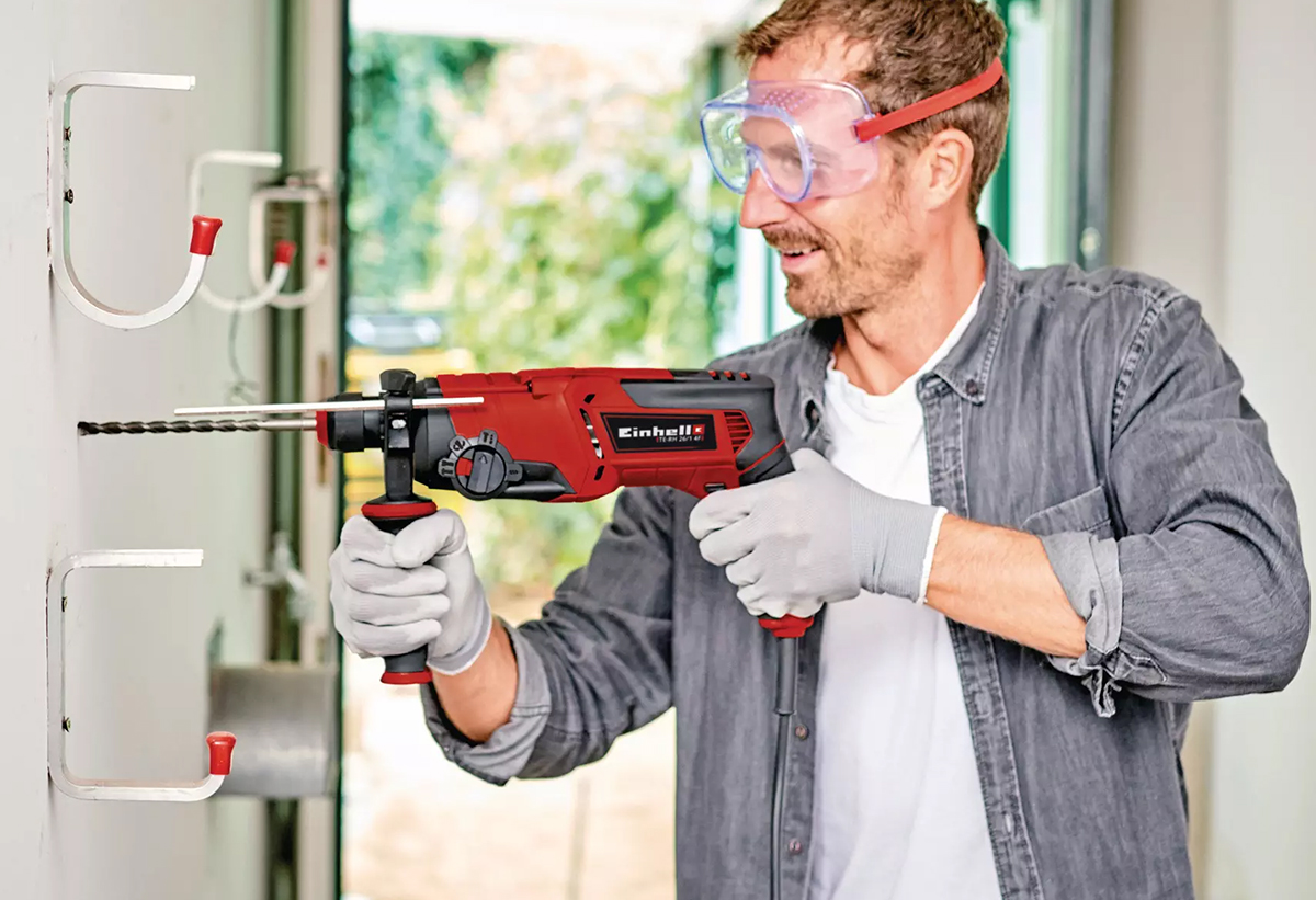 Απεικονίζεται άνδρας με προστατευτικά γυαλιά να χρησιμοποιεί το πιστολέτο στον τοίχο.